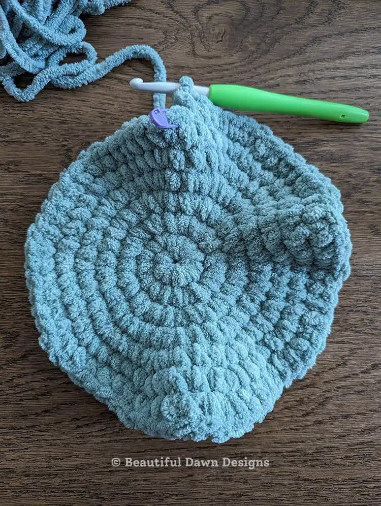 A large, flat crocheted circle demonstrating the progress before folding to create the moon pillow's crescent shape. Moon Pillow Crochet Pattern round 14.