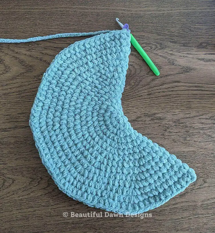 Hands stuffing a partially crocheted moon pillow with Poly-fil, illustrating the filling process for a plump finish. Moon Pillow Crochet Pattern stuffing.