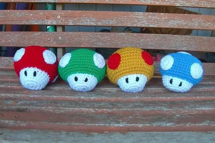 A pair of crocheted Toad and Toadette figures from Super Mario, featuring their iconic vests and mushroom caps, perfect for fans.