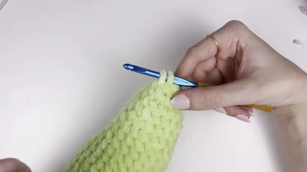 Crochet bass fish body in progress with side fins seamlessly attached, illustrating the no-sew technique.