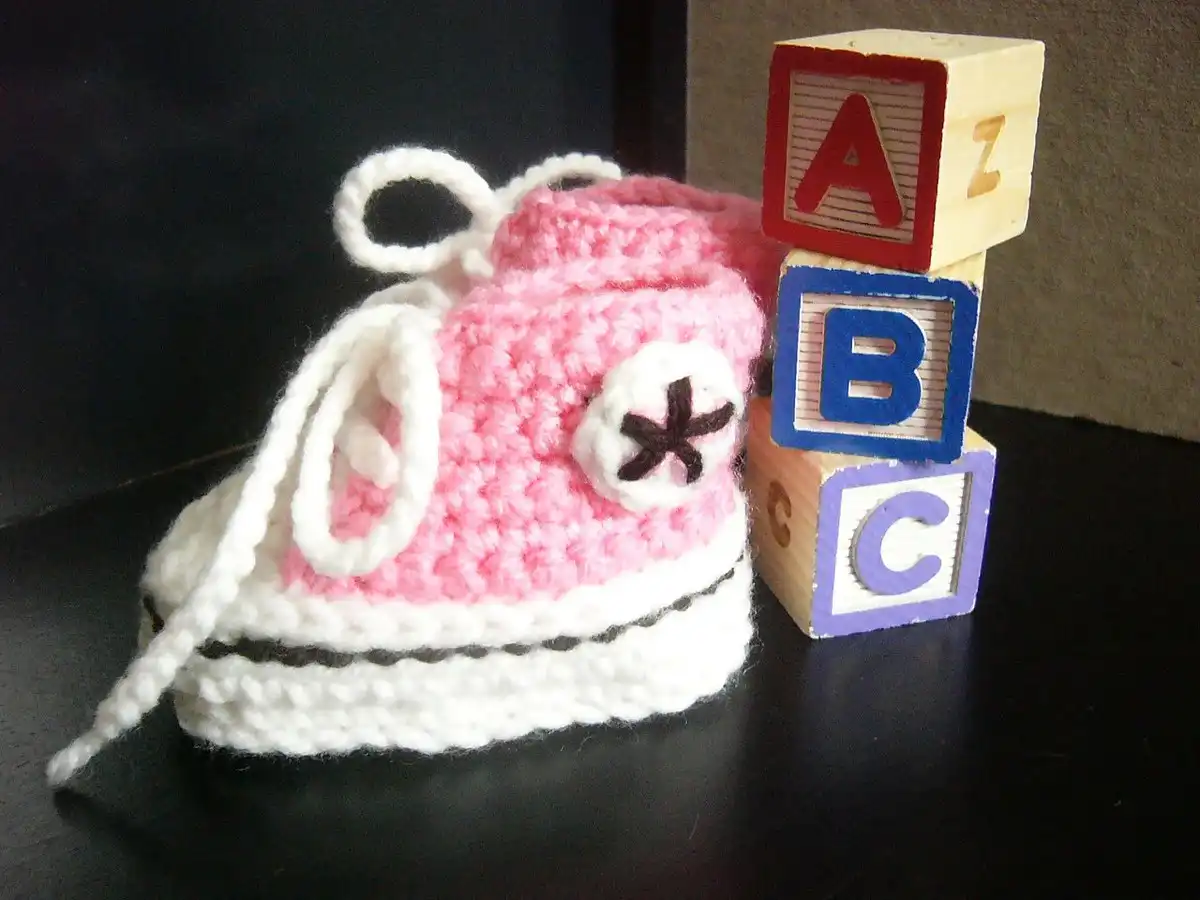 Close-up of a pair of detailed crocheted Converse sneaker-styled baby booties, showcasing craftsmanship.