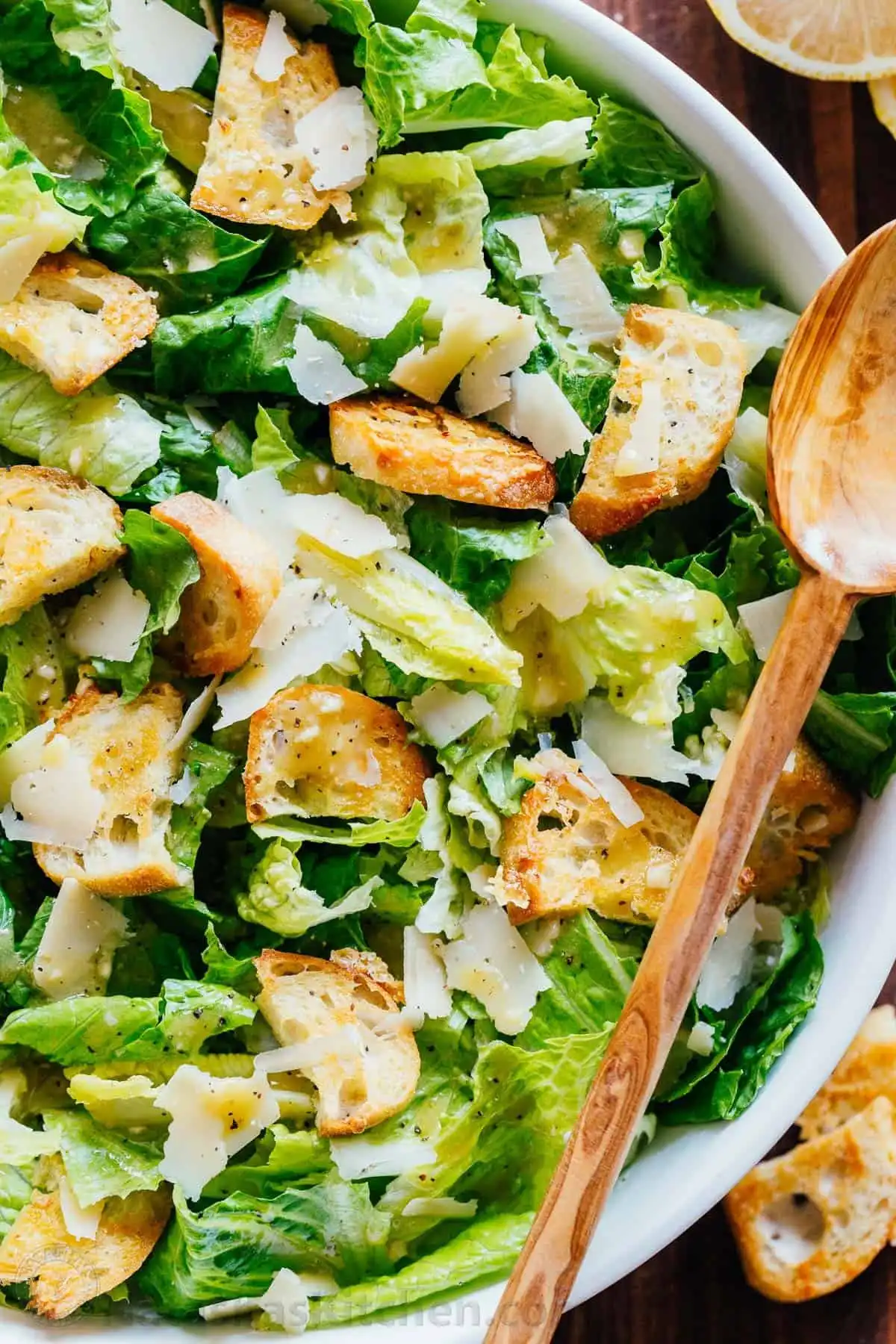 A vibrant romaine salad with croutons, shaved Parmesan, and a light drizzle of Caesar dressing, ready for serving.