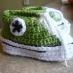 Two pairs of crochet Converse baby booties in vibrant green and red, styled like iconic sneakers.