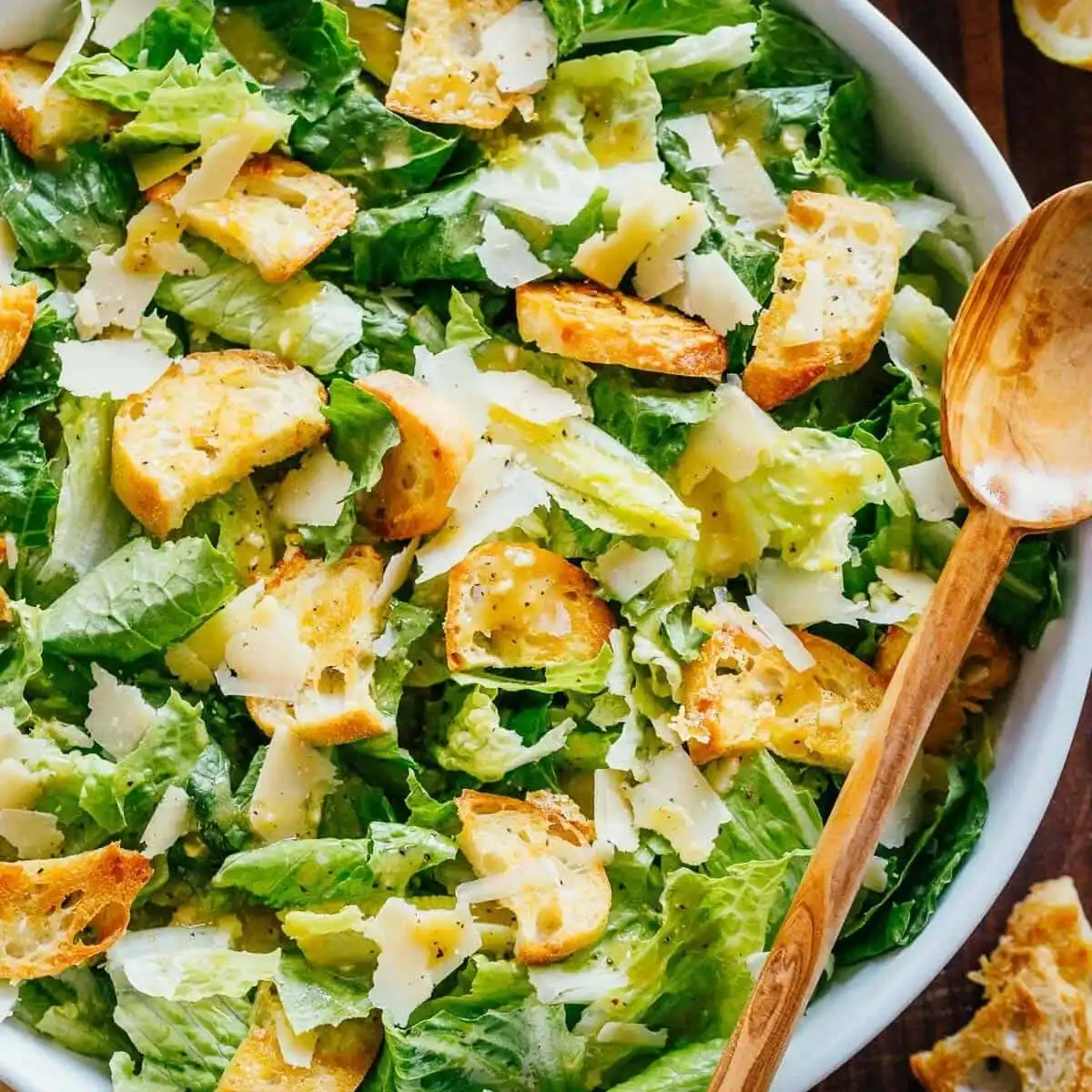 A close-up shot of a classic Caesar Salad in a rustic bowl, showcasing the crisp romaine, golden croutons, and rich Parmesan cheese.