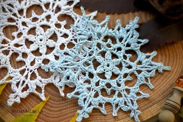 The 'Goldfinch Snowflake' crochet pattern in golden-yellow yarn, featuring a beautiful sun motif at its center.
