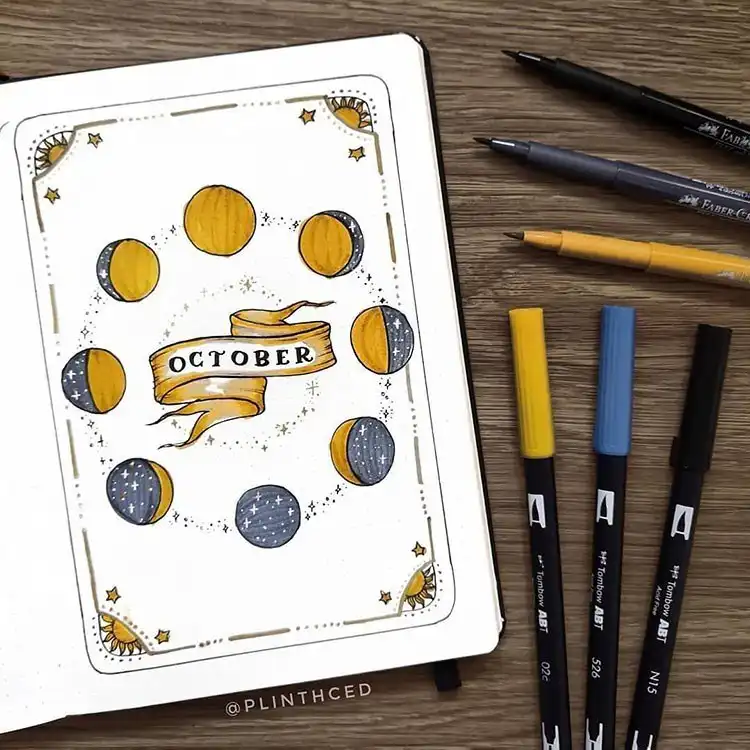 October bullet journal spread showcasing blue and gold leaves, with the title written on brown paper.