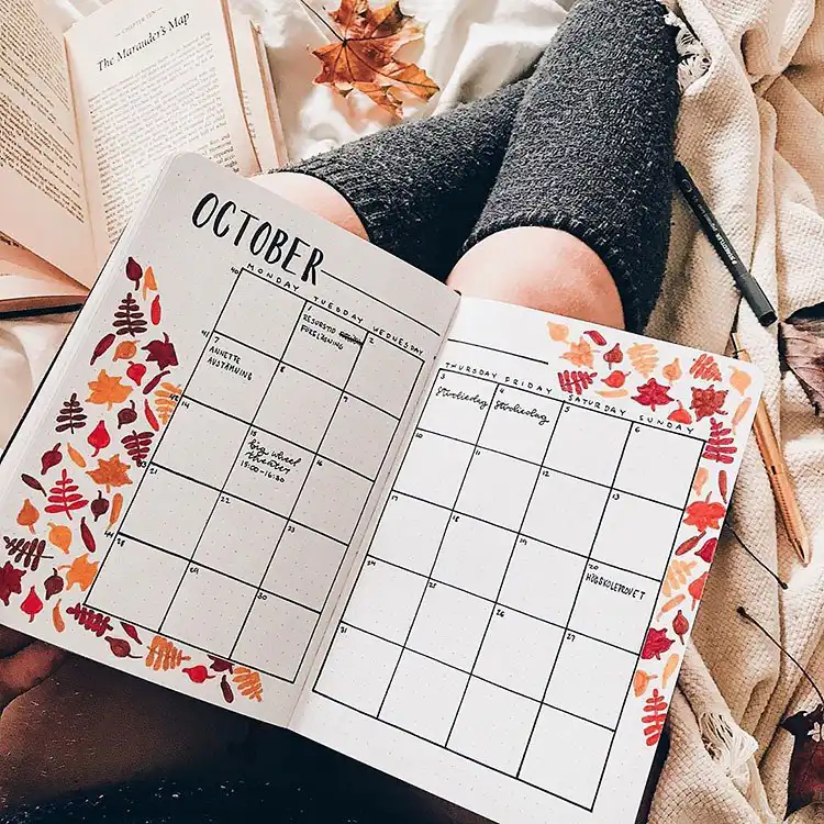 Bullet journal spread featuring a comforting cup of tea surrounded by autumnal colors and leaves.