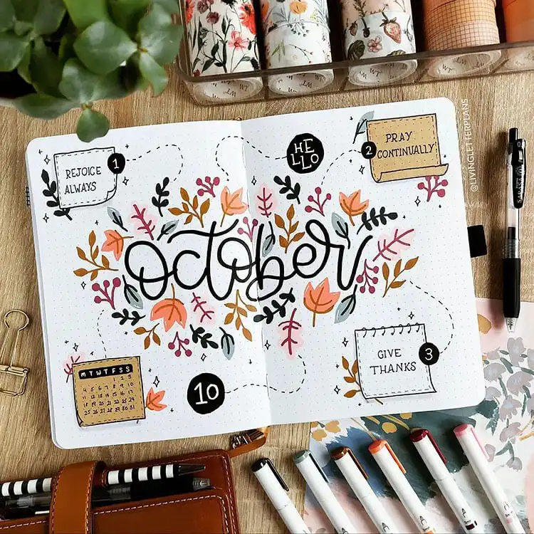 October bullet journal cover page with a rich floral border of autumn leaves and berries framing the month title.
