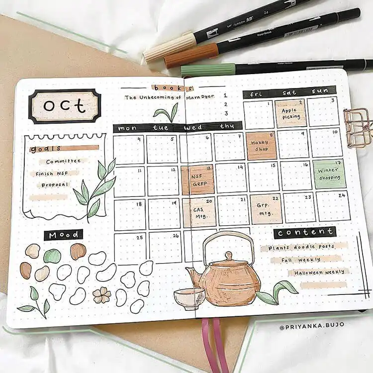 Hand-drawn October bullet journal calendar featuring whimsical teapots and scattered autumn leaves.