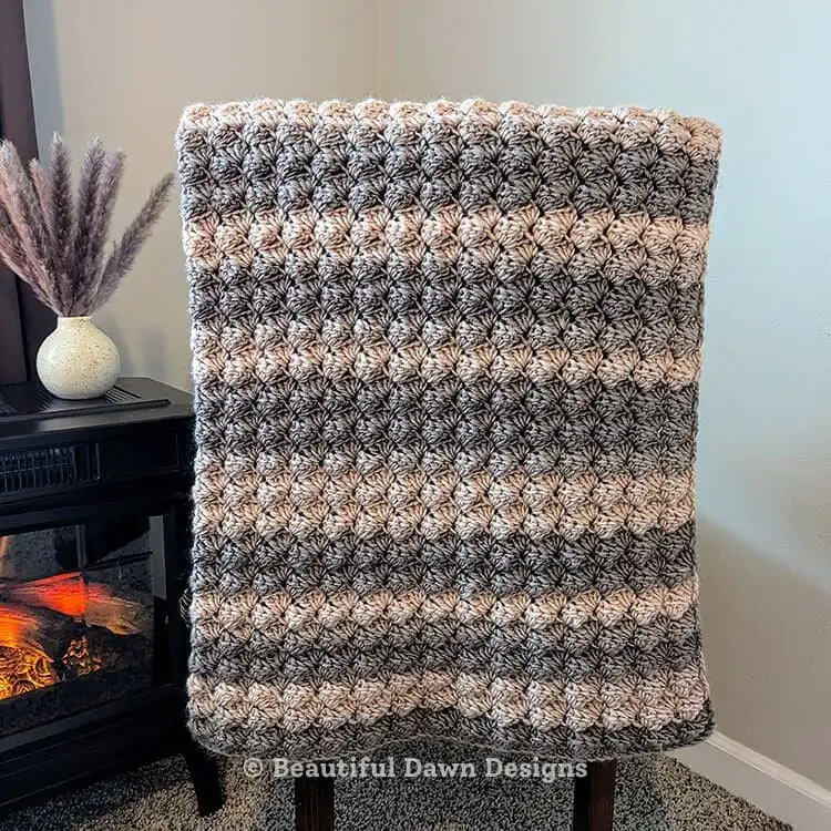 Woodland crochet blanket displayed on a bed, emphasizing the generous dimensions of the One-Row Repeat Easy Crochet Blanket Pattern