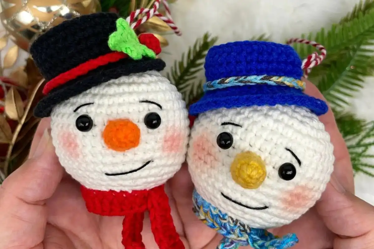 Personalized Christmas Baubles – Custom & Free Crochet Ornament Patterns 3 A pair of classic crocheted Christmas Ornaments, featuring a Santa Claus and a snowman, hanging on a rustic wooden star frame with pine branches.