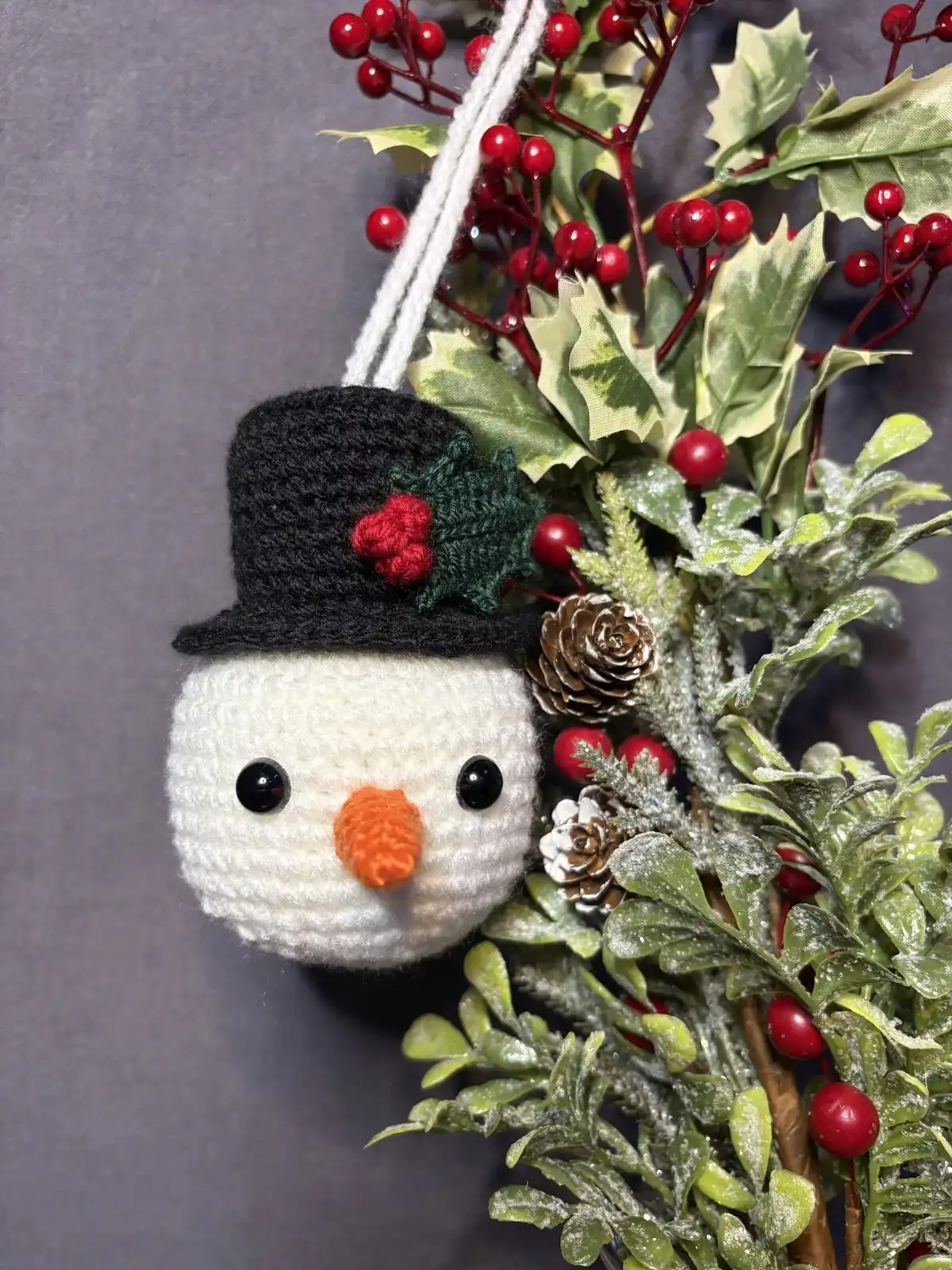Personalized Christmas Baubles – Custom & Free Crochet Ornament Patterns 9 An elegant display of small, intricately crocheted Christmas Ornaments including a snowman, penguin, and green frog, arranged on a pine branch.