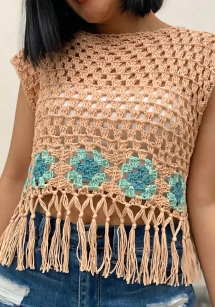 Crocheted beige crop top with blue and green granny squares and fringe, a free pattern for a boho look.