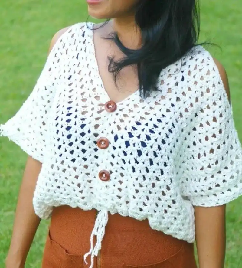 White crochet boho top with brown buttons and drawstring waist, paired with rust-colored pants for a chic look.