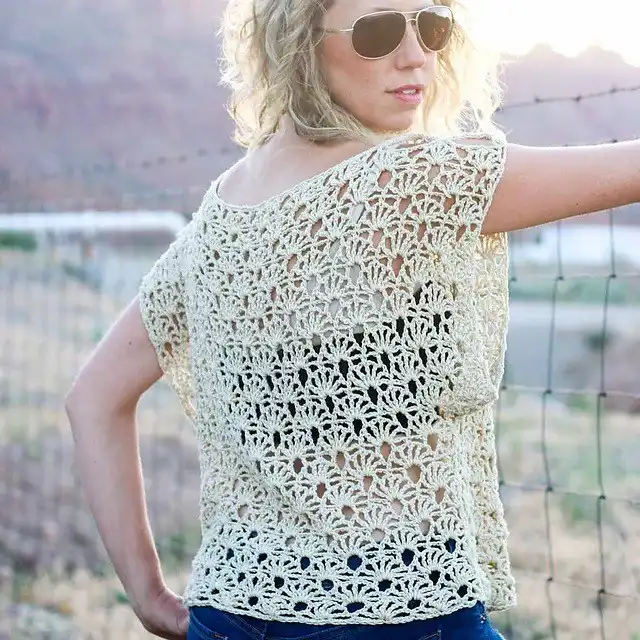 Woman wearing a lacy cream-colored Canyonlands Boho Crochet Top outdoors, showcasing open fan stitch.
