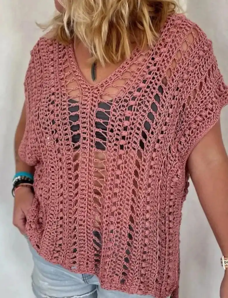 Person wearing a loose pink Heaven Tee crochet top over a black tank, a relaxed oversized boho style.