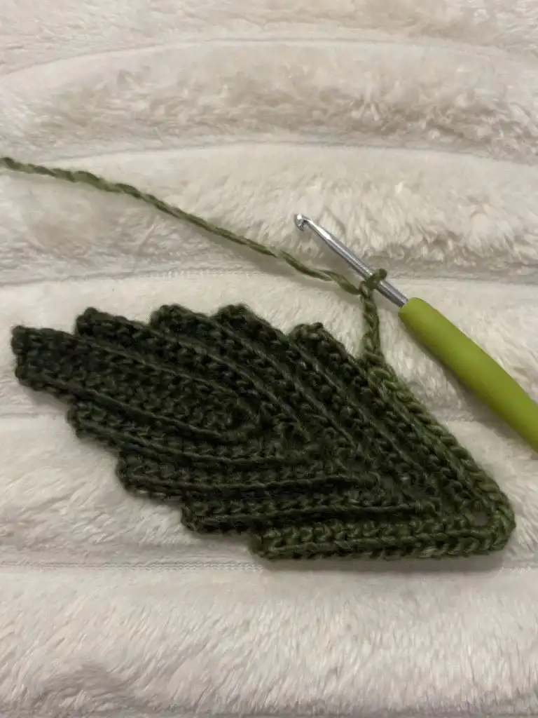 Another angle of the completed green crochet leaf, highlighting its delicate curves and texture.
