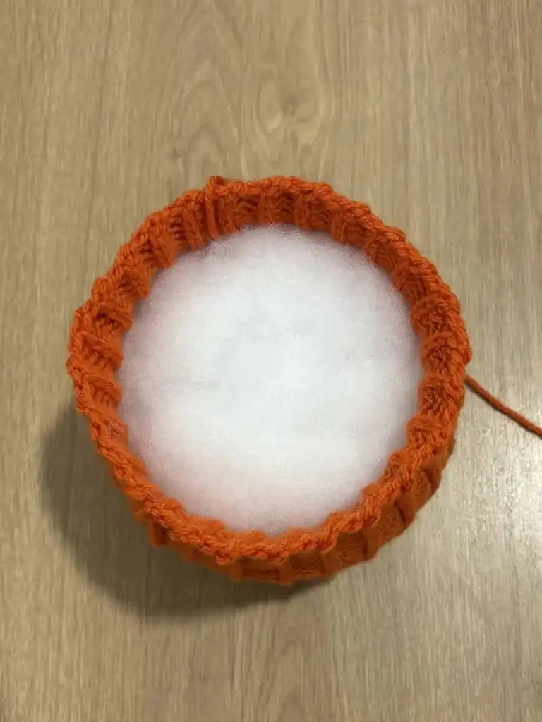 The top of the pumpkin secured after being pulled tight, showing the almost complete spherical shape.