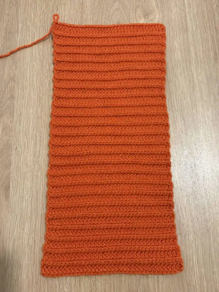 A small, cylindrical piece of brown crocheted fabric, illustrating the initial rounds of the stem for the Pumpkin Free Crochet Pattern.