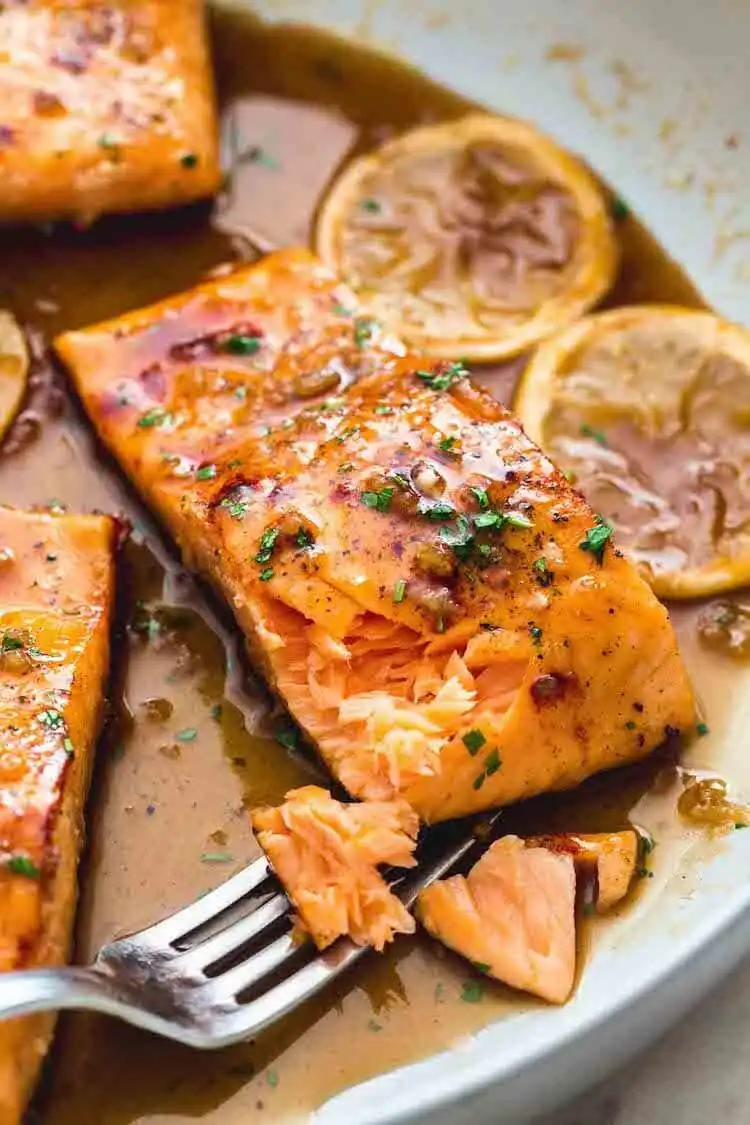 Honey Garlic Salmon fillet with a sticky, caramelized glaze, garnished with sesame seeds and green onions.