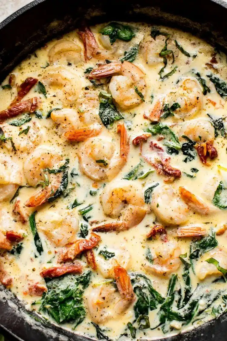 Easy Creamy Tuscan Shrimp in a skillet, with spinach, sun-dried tomatoes, and a rich cream sauce.