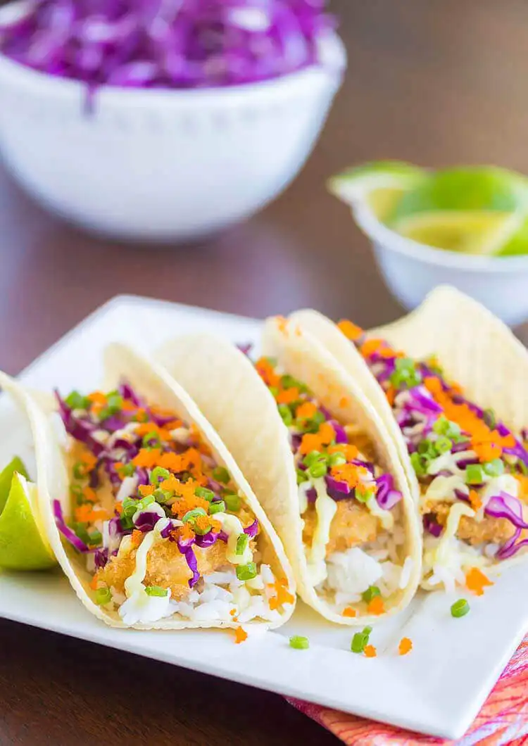Epic Baja Fish Tacos with avocado crema, filled with crispy fish, slaw, and topped with fresh cilantro.