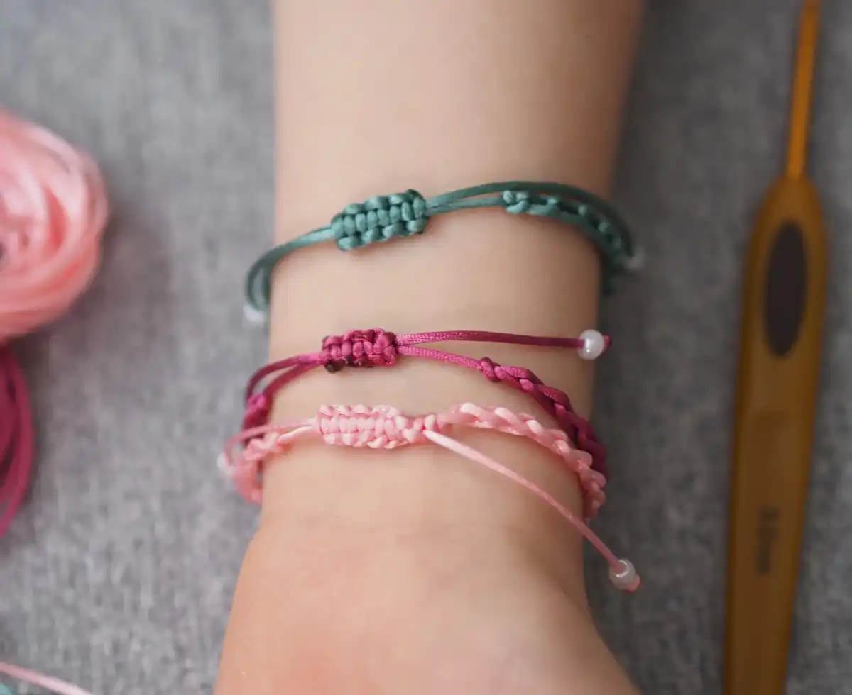 A collection of finished chain stitch friendship bracelets in various hues, some adorned with beads, demonstrating final results of the free pattern.