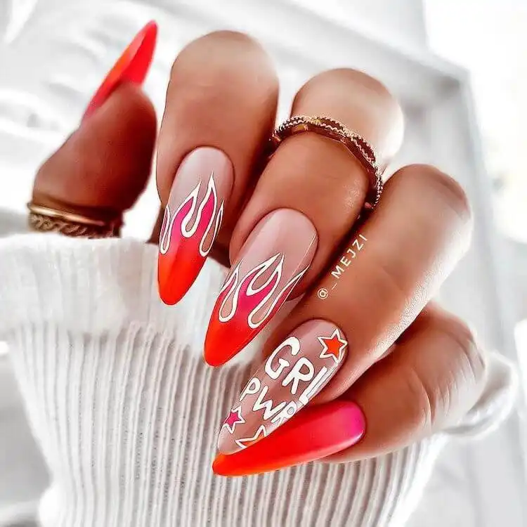 Red and pink gradient flame acrylic nails on a coffin shape with white outlines, creating a fiery and dynamic look.