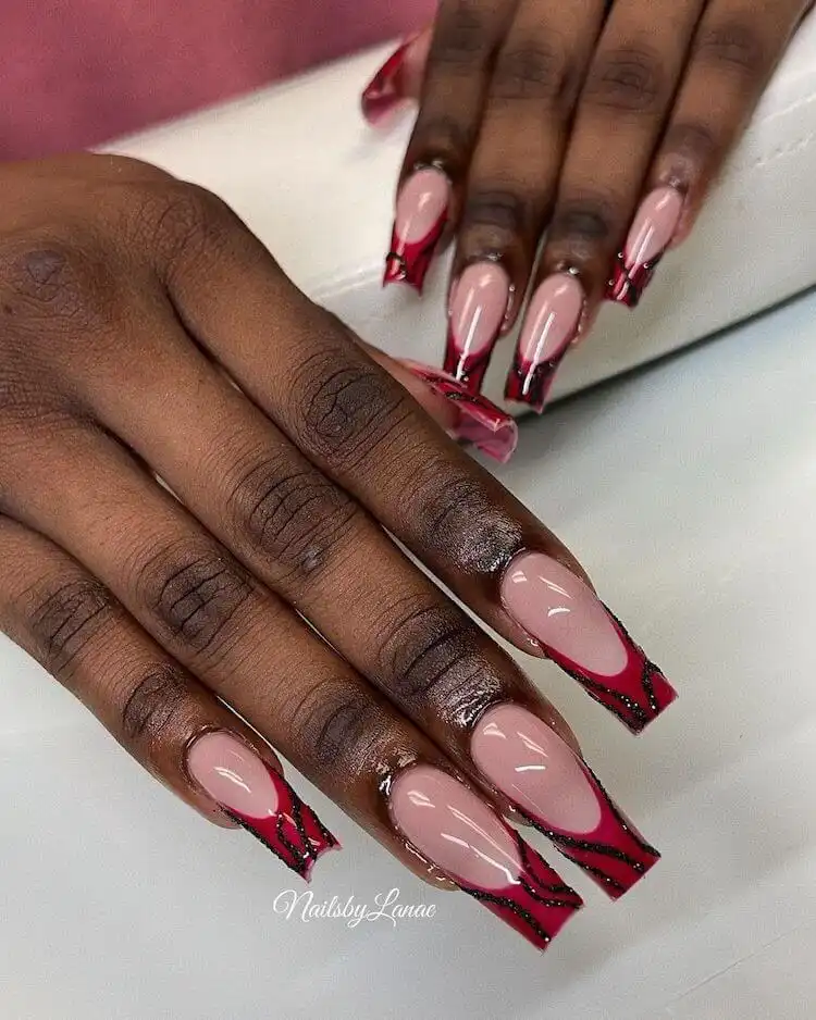 Modern red acrylic nails outlined with crisp white polish around the edges, offering a trendy and clean look.