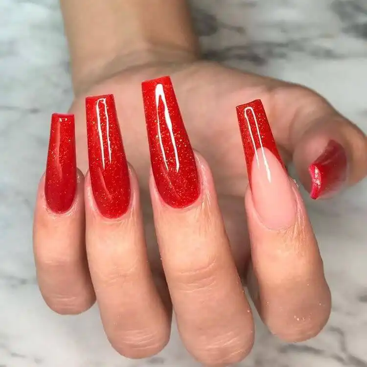 Sparkling red coffin acrylic nails adorned with an abundance of glitter and rhinestones for maximum impact.
