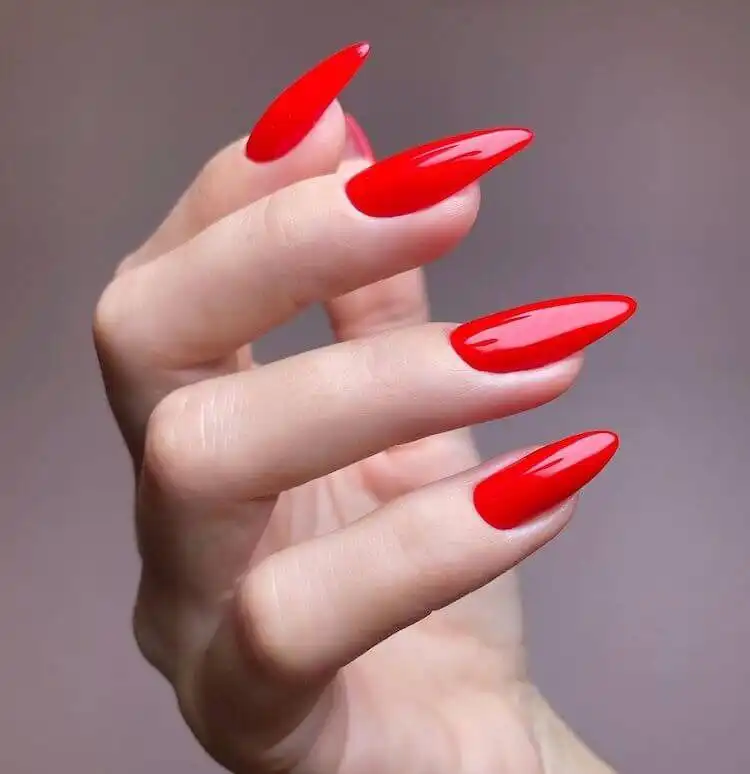 Classy red acrylic nails with rich polish and subtle rhinestone embellishments, timeless and sophisticated.