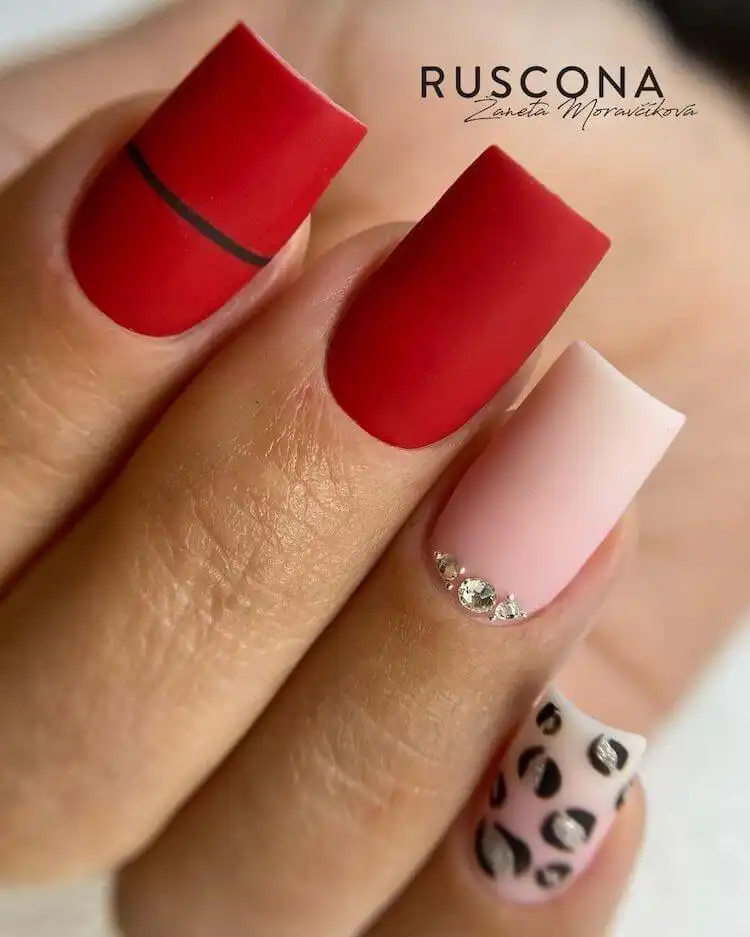 Red and pink gradient acrylic nails decorated with intricate white leaf designs covering the full nail surface.