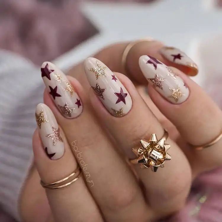 Stunning Blue Nail Designs - Perfect Winter Nail Design Ideas 25 Cute Stars nail design with burgundy and gold on a nude base, adding celestial charm to perfect winter nail design ideas.