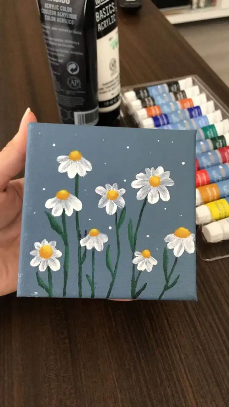 Close-up acrylic painting of daisies on a small canvas, focusing on their delicate white petals.