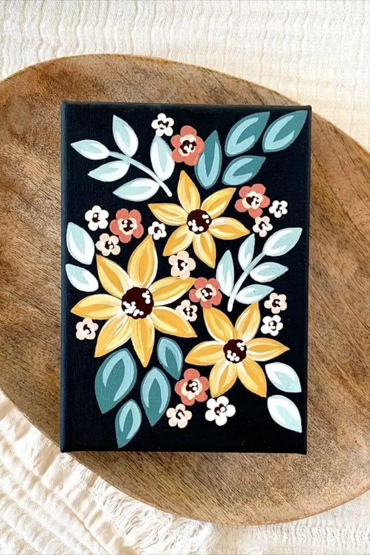 Yellow, blue, and coral flowers painted with bold acrylics on a dark canvas, creating a captivating contrast.