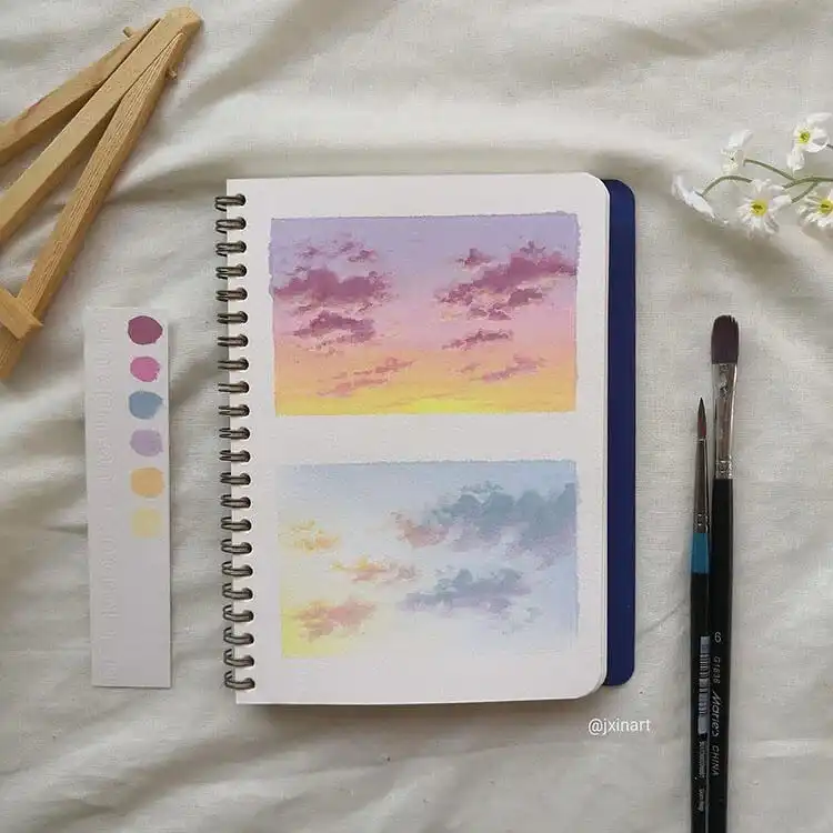 Two watercolor paintings showcasing delicate purple and blue cloud formations, serene and calming.