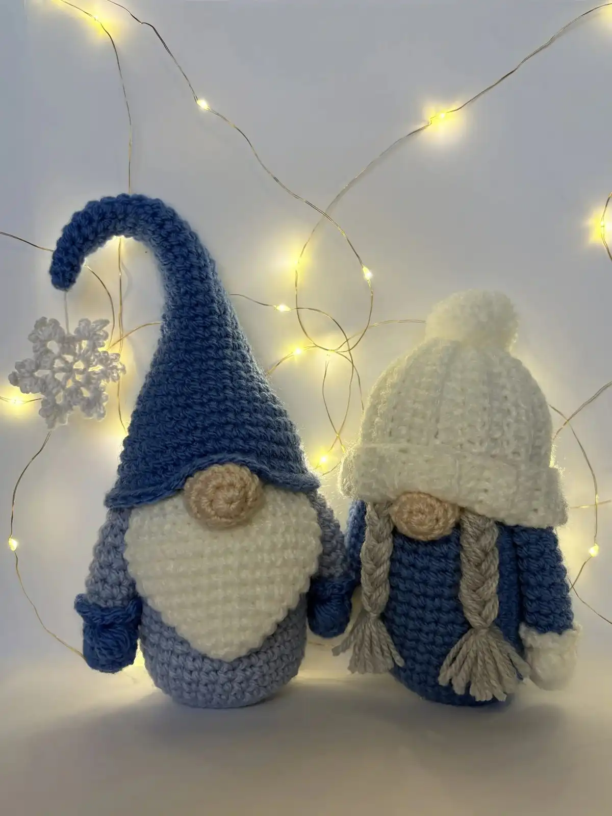 A crocheted Santa Claus Gnome with a red hat, white beard, and round nose, sitting on a textured background, ready for Christmas.