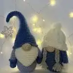 A handmade Christmas Gnome Amigurumi with a striped red, blue, and gray hat and a fluffy white beard, showcasing festive detail.