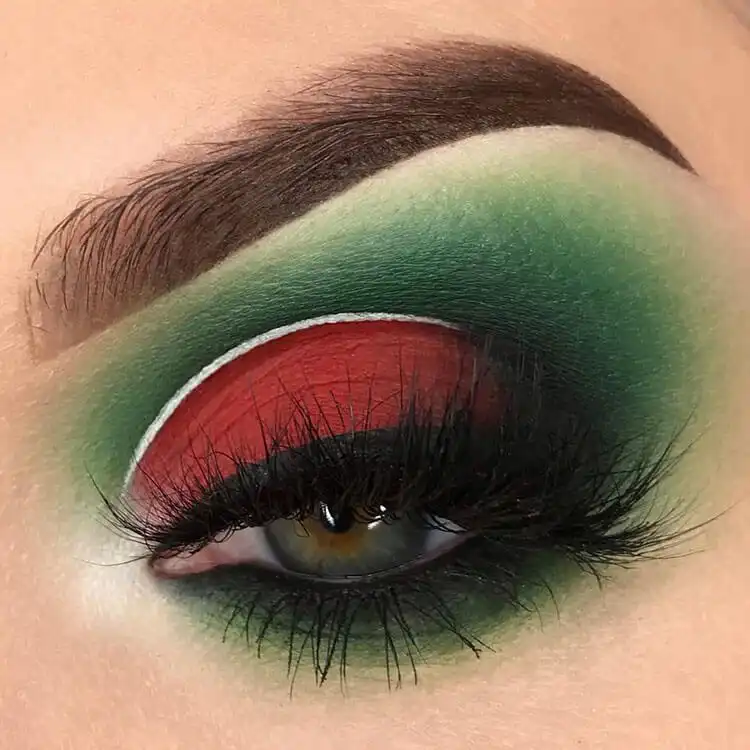 Creative Grinch-inspired eye makeup with bright red and green shadows and white eyeliner details.