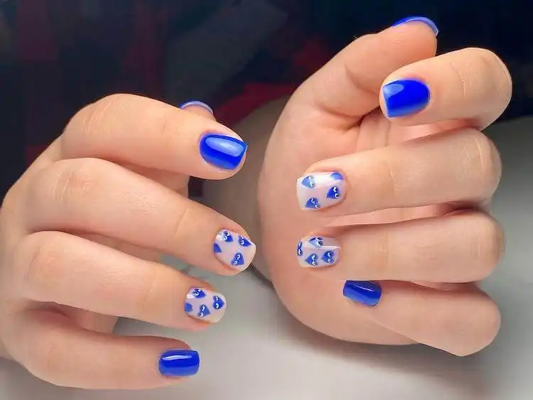 Blue nails adorned with Comme des Garçons heart motifs, a wonderful blue nail design that is bold and classic for a fun look.