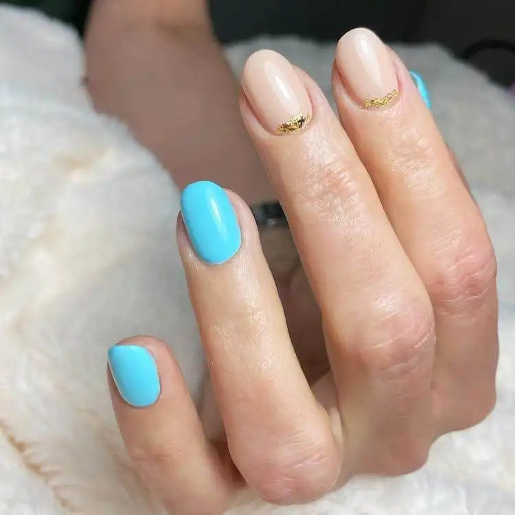 Luxurious blue nails with delicate golden foil accents, a wonderful blue nail design that is both bold and classic.