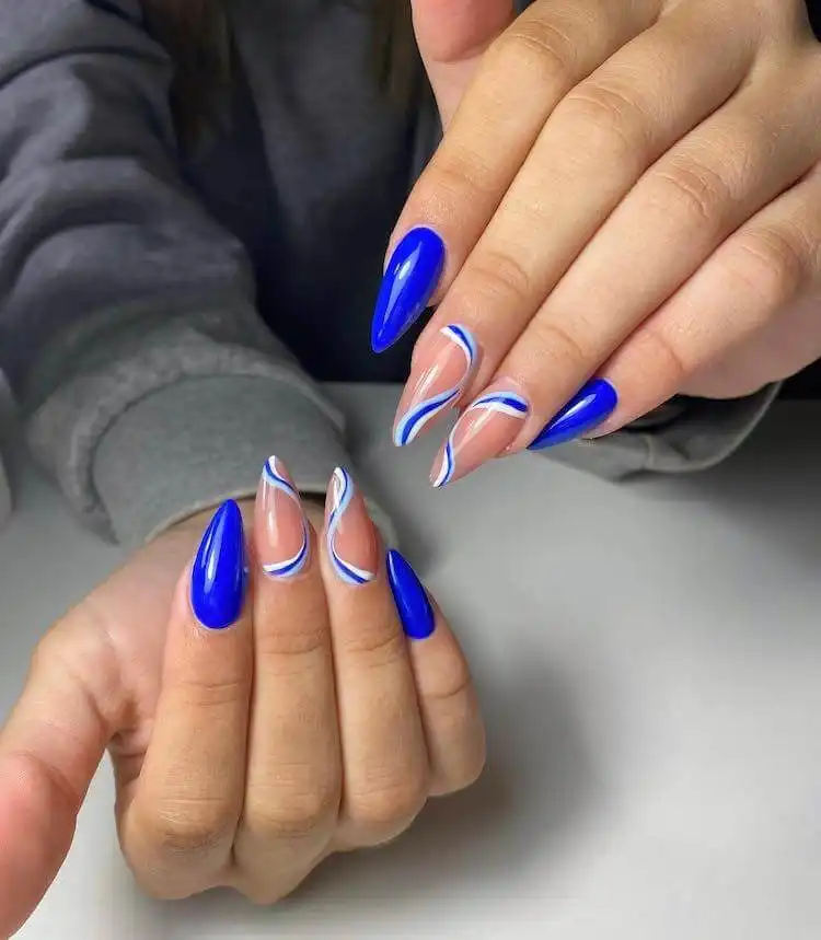Artistic blue and white swirl nails featuring two shades of blue, a wonderful blue nail design that is bold and classic.