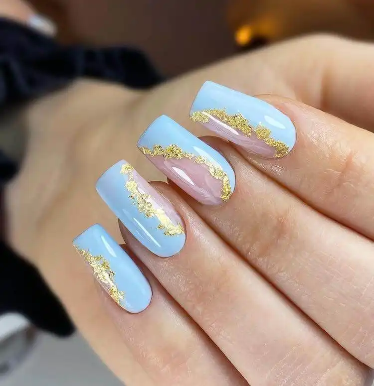 Soft baby blue manicure with subtle gold foil accents, a wonderful blue nail design that is classic and elegant.