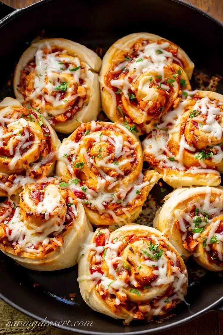 Close-up of cheesy BBQ chicken pizza rolls arranged on a plate, with golden crusts and visible fillings.