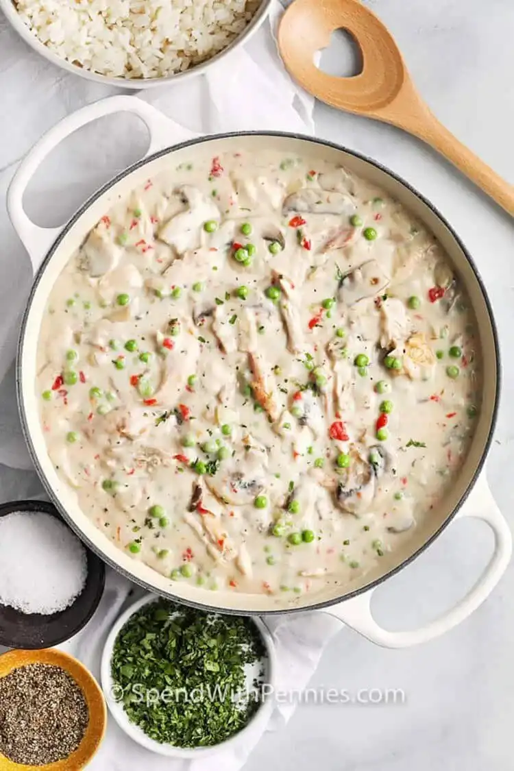 A plate of creamy chicken ala king served over fluffy rice, garnished with parsley.