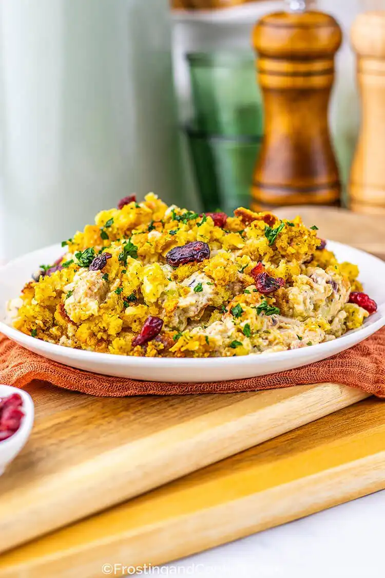 A baked harvest chicken and stuffing bake, showing a golden stuffing crust, creamy chicken, cranberries, and melted cheese.